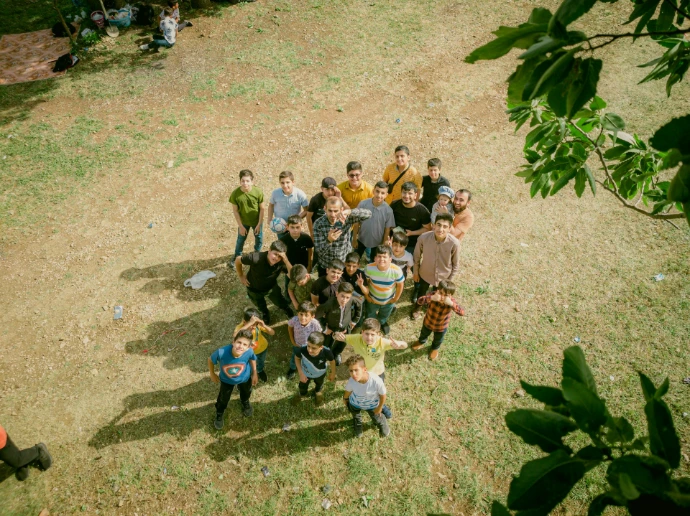 a group of people standing on top of a grass covered field